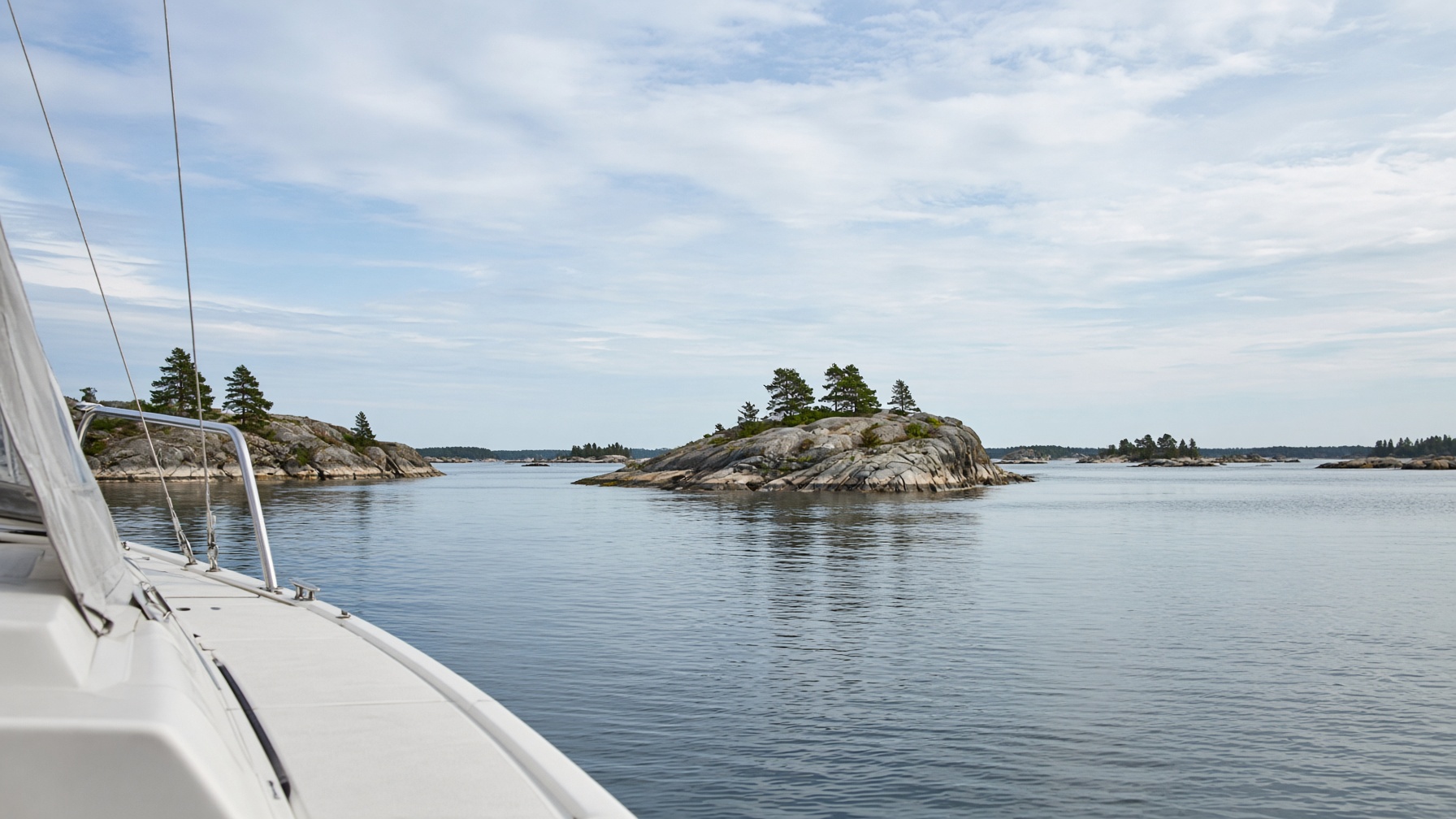 Calm water and low pine islands in the Finnish archipelago, seen from a small boat.